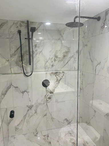 Marble tile shower recess with black rain shower and fixtures